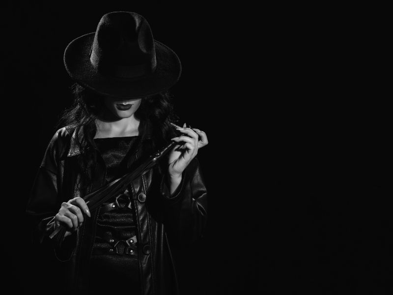 femme dominatrice avec un martinet et un chapeau
